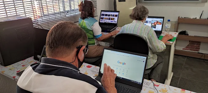 Alunos da terceira idade usando notebooks em aula de informática